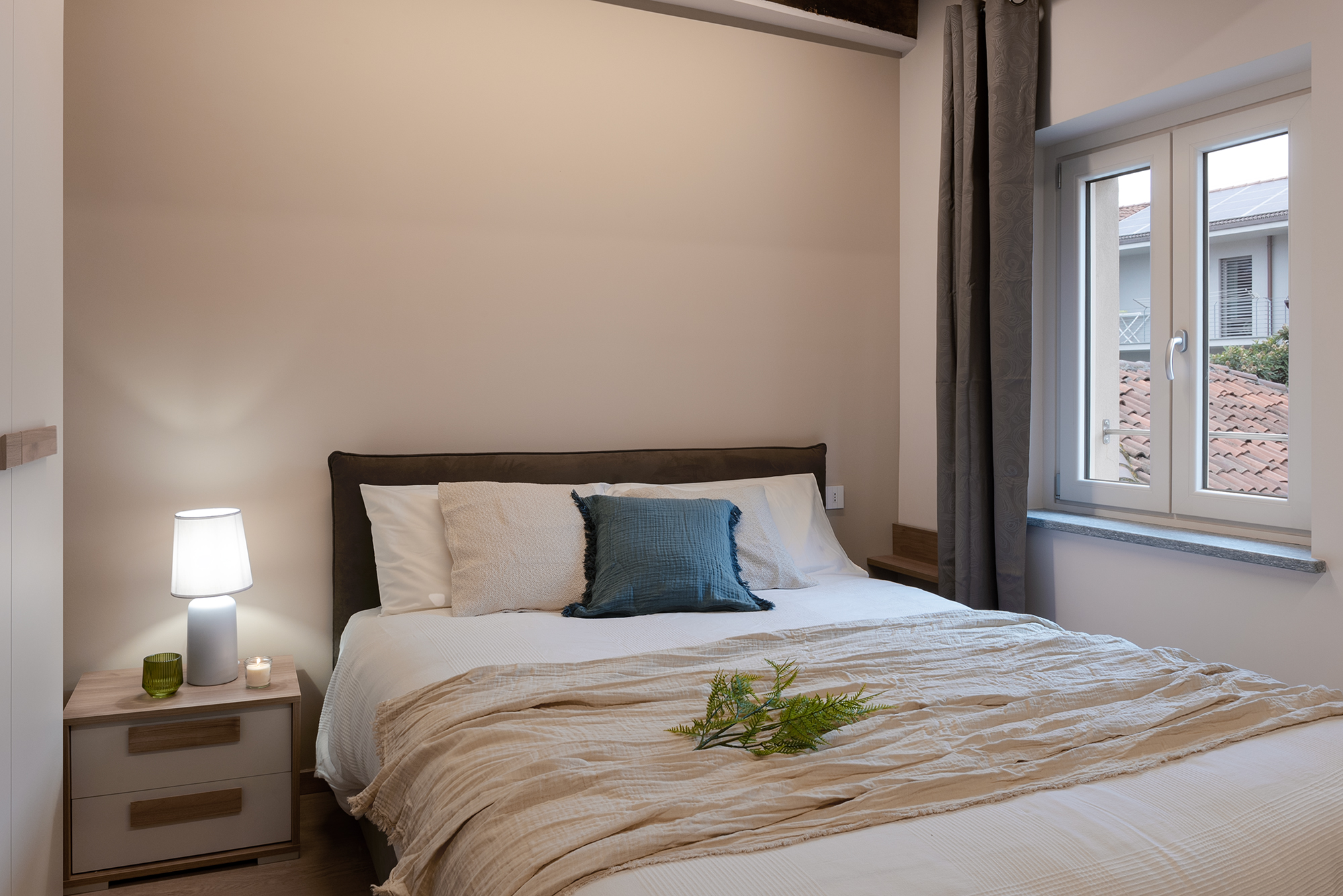 Il letto matrimoniale con lenzuola chiare La cucina con basi e frigo blu e pensili bianchi, travi a vista e tavolo da pranzo rotondo bianco nel bilocale in affitto a Savigliano Schiaparelli