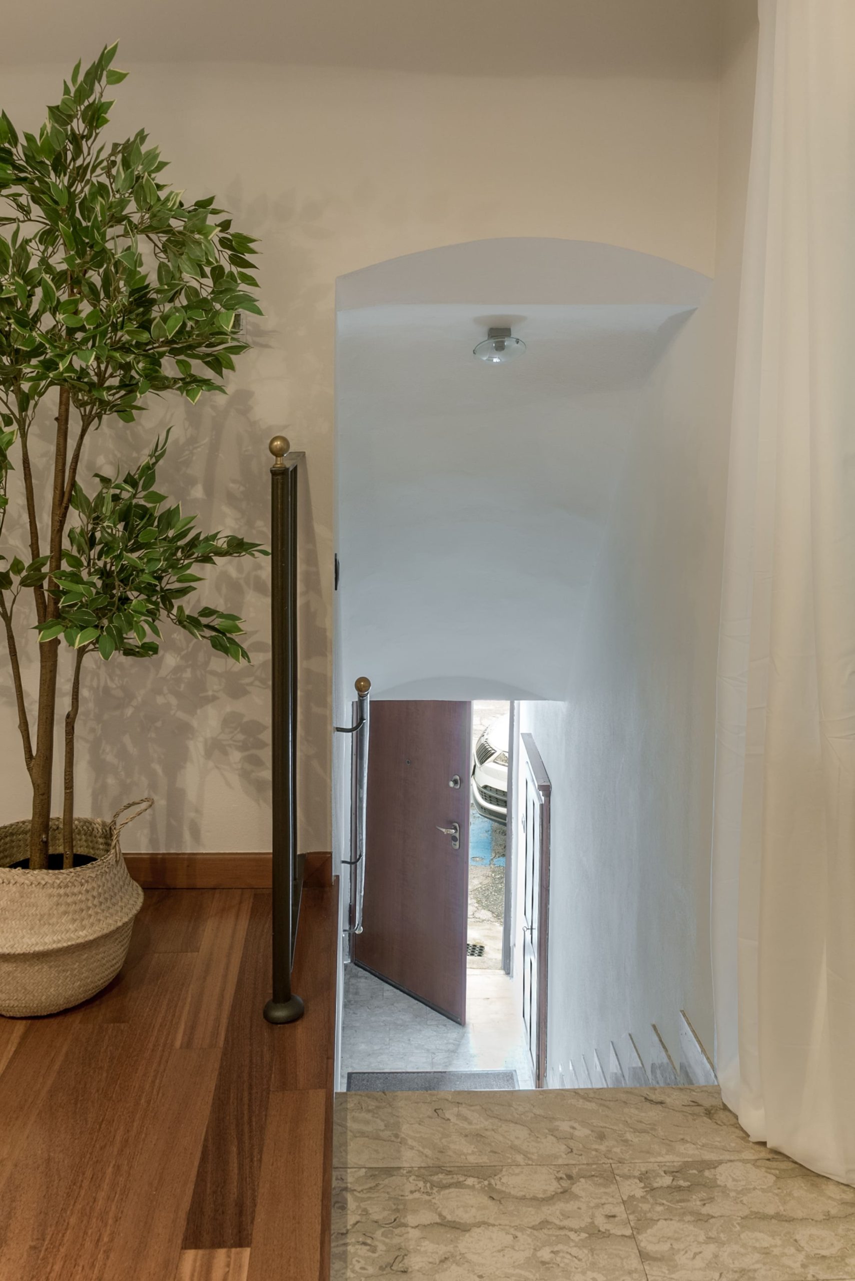 L'ingresso della casa in affitto a Savigliano: il portone aperto dà su una rampa di scale che conduce al salotto di cui si vede una pianta