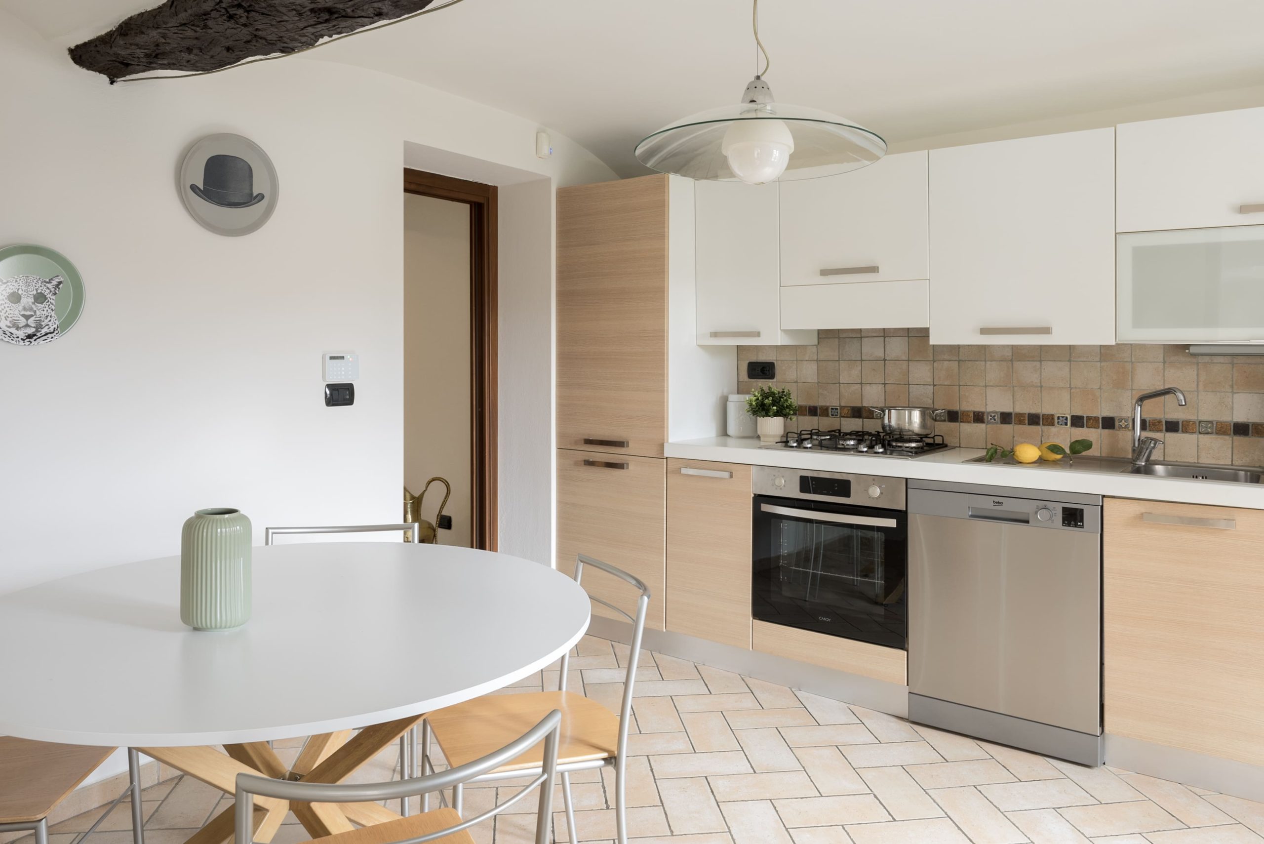 La cucina lineare in legno chiaro con, in primo piano, un tavolo da pranzo bianco e rotondo nella casa in affitto a Savigliano