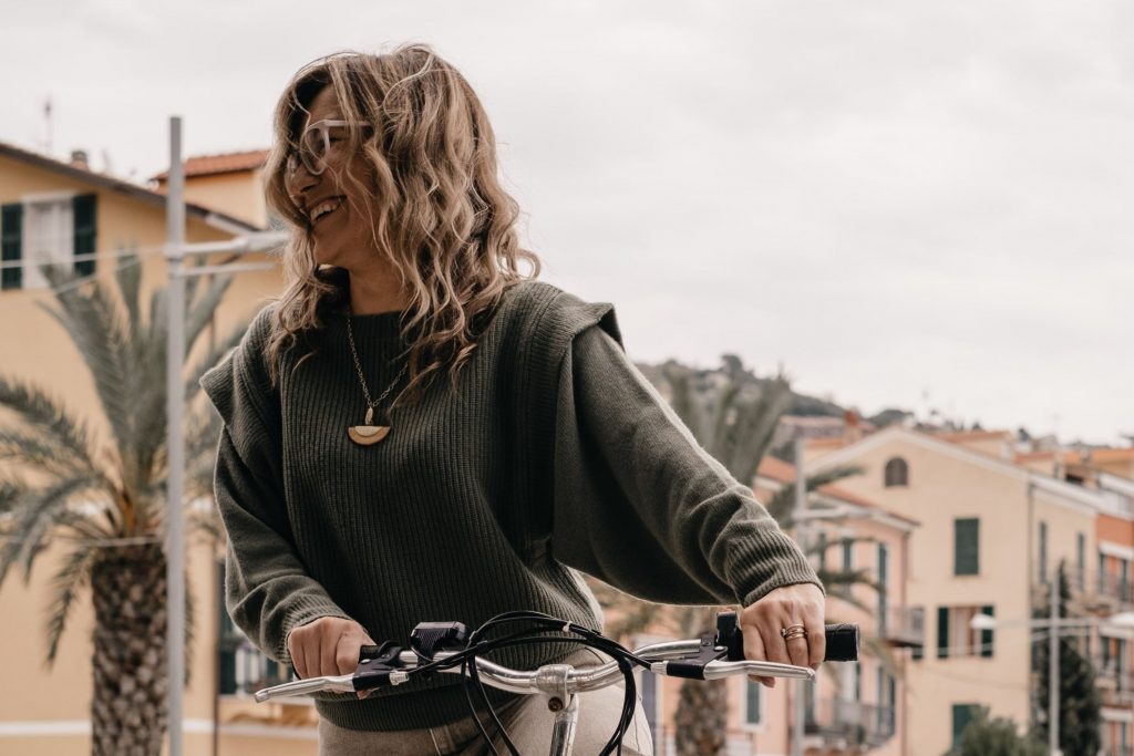 Floriana, die Seele von Vayadù, lächelt, als sie auf das Fahrrad steigt, das sie in Ospedaletti gemietet hat, und sich auf den Radweg des Küstenparks Riviera dei Fiori begibt.