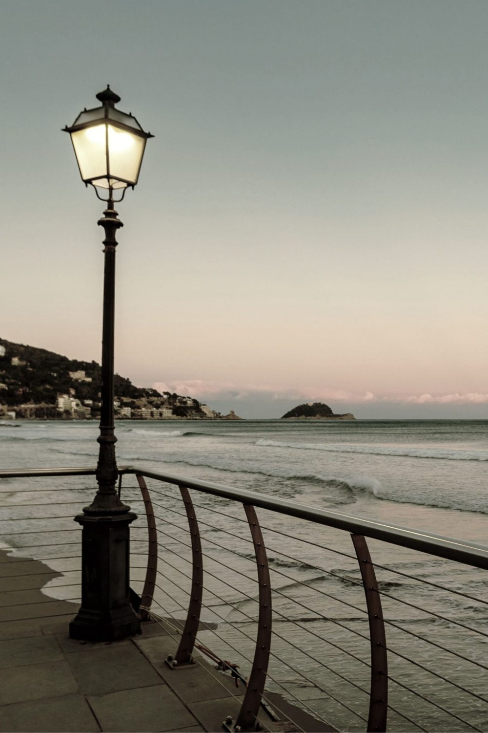 Il lungomare di Alassio al tramonto in inverno, nel momento in cui si accendono i lampioni.
