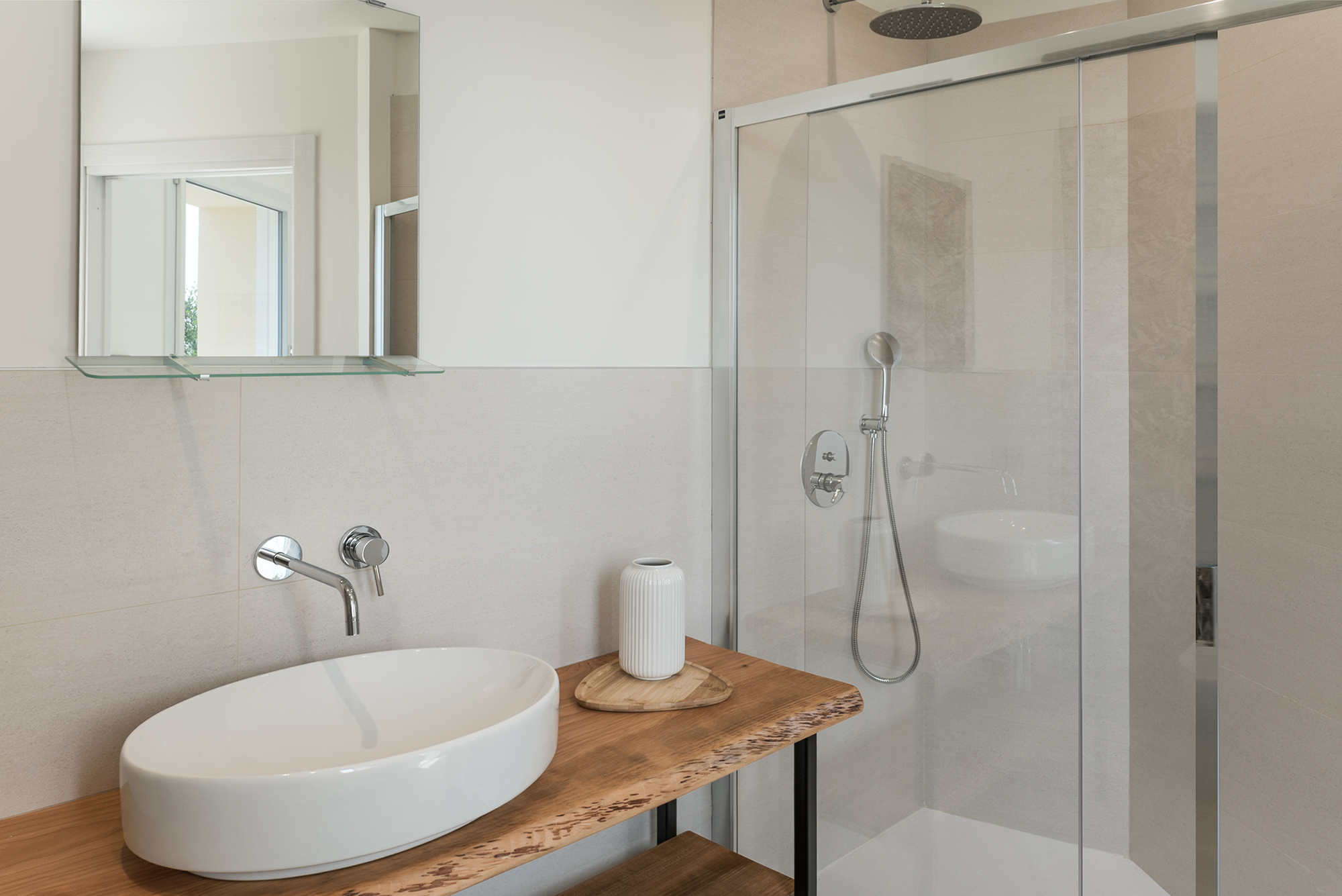 Il lavabo da appoggio, il piano in legno e la doccia nel bagno della casa vacanza a Finale Ligure