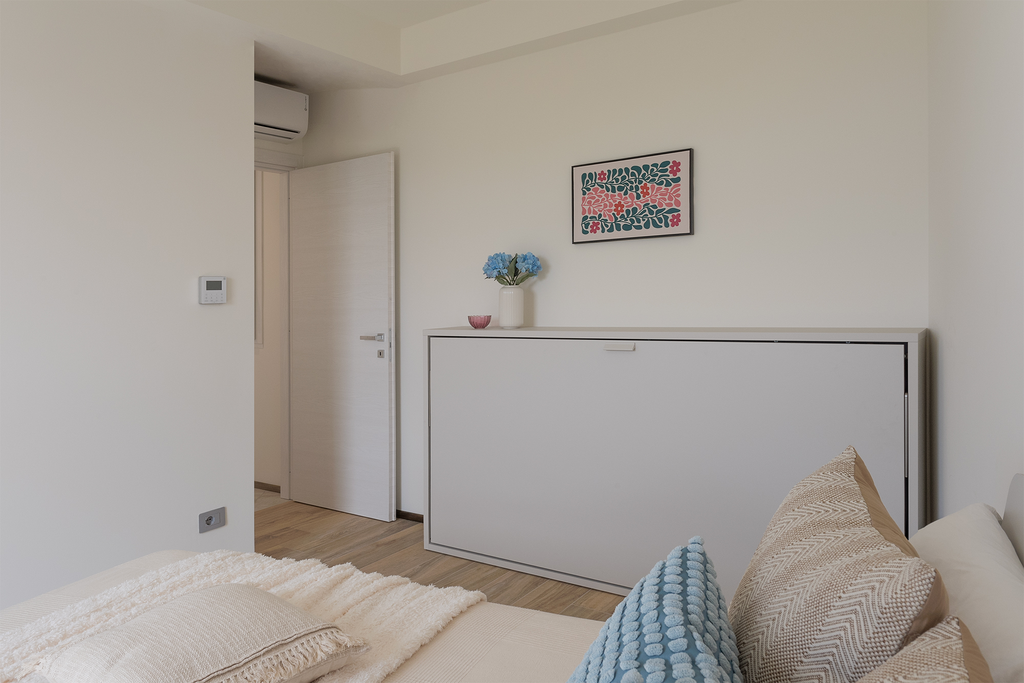 Un pezzo del letto matrimoniale e il letto a ribalta chiuso nella seconda stanza della casa vacanza a Finale Ligure