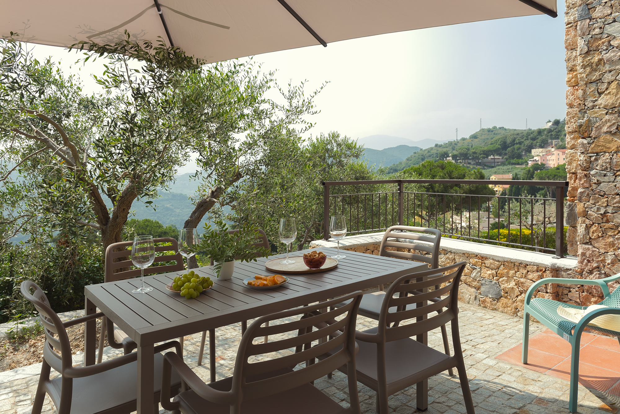 Il tavolo da esterno con sedie e ombrellone sul terrazzo in pietra della casa vacanza a Finale Ligure