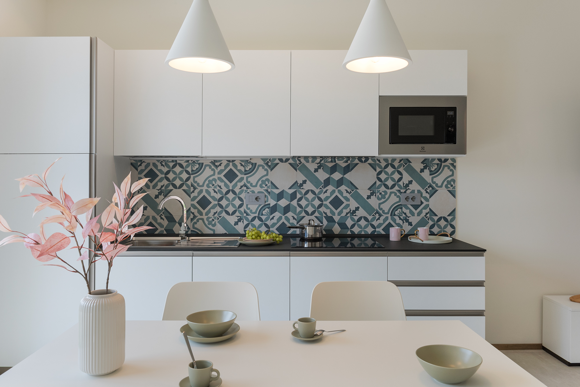 La cucina bianca, moderna e con piastrelle blu e una porzione di tavolo e sedie della casa vacanza a Finale Ligure
