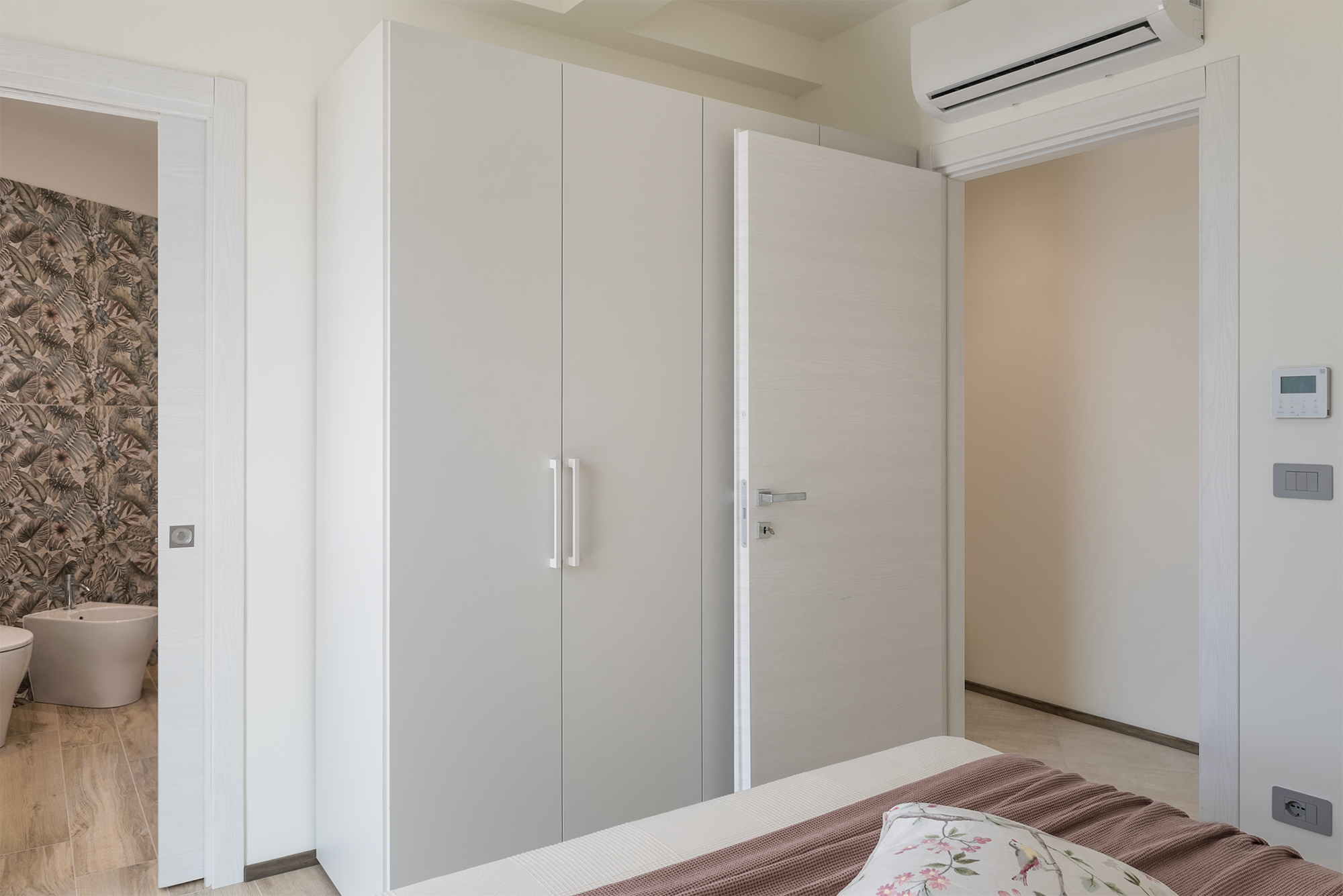 L'armadio a 4 ante e la porta aperta sul bagno en suite della camera matrimoniale della casa vacanza a Finale Ligure