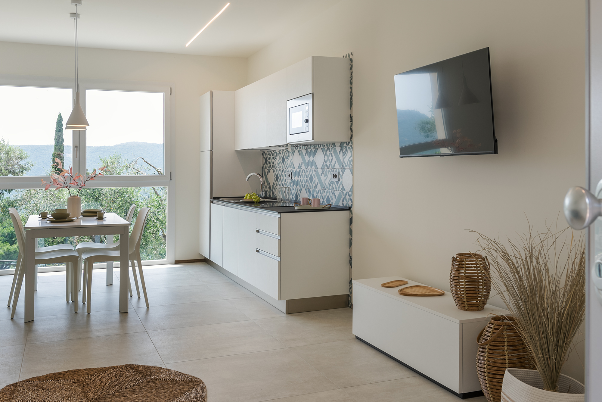 Il living con cucina e tavolo per 4 persone che affaccia sul giardino e le colline della casa vacanza a Finale Ligure